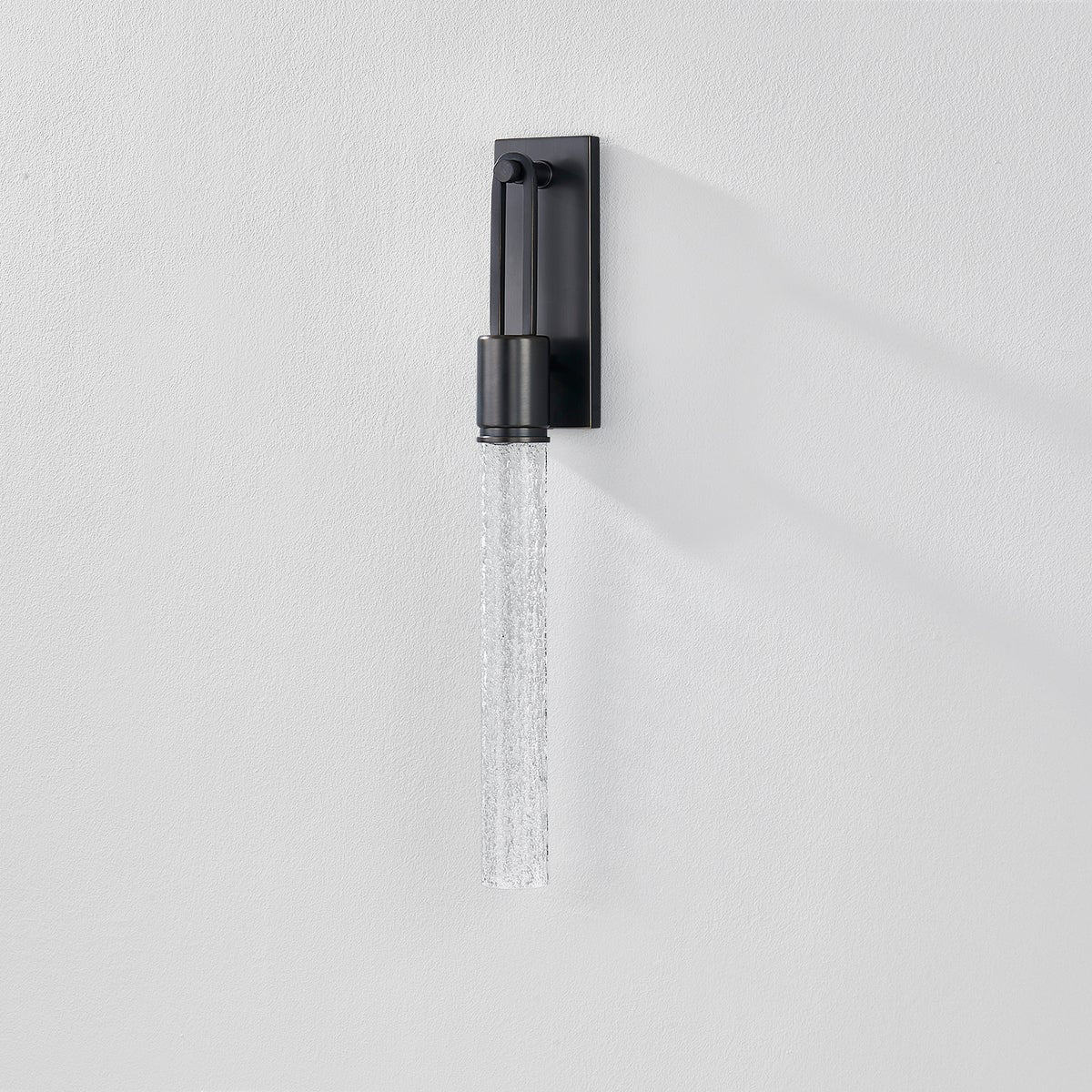 Close-up of the Raynham Wall Sconce in dark bronze showing the arm curve and shade silhouette.