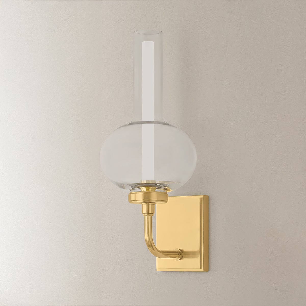 Rossman Wall Sconce in aged brass shown from the front to reveal the arm curve and shade silhouette.