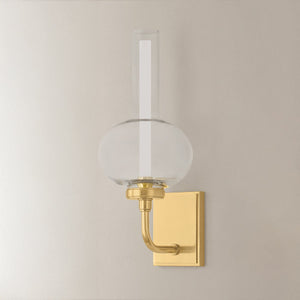 Rossman Wall Sconce in aged brass shown from the front to reveal the arm curve and shade silhouette.