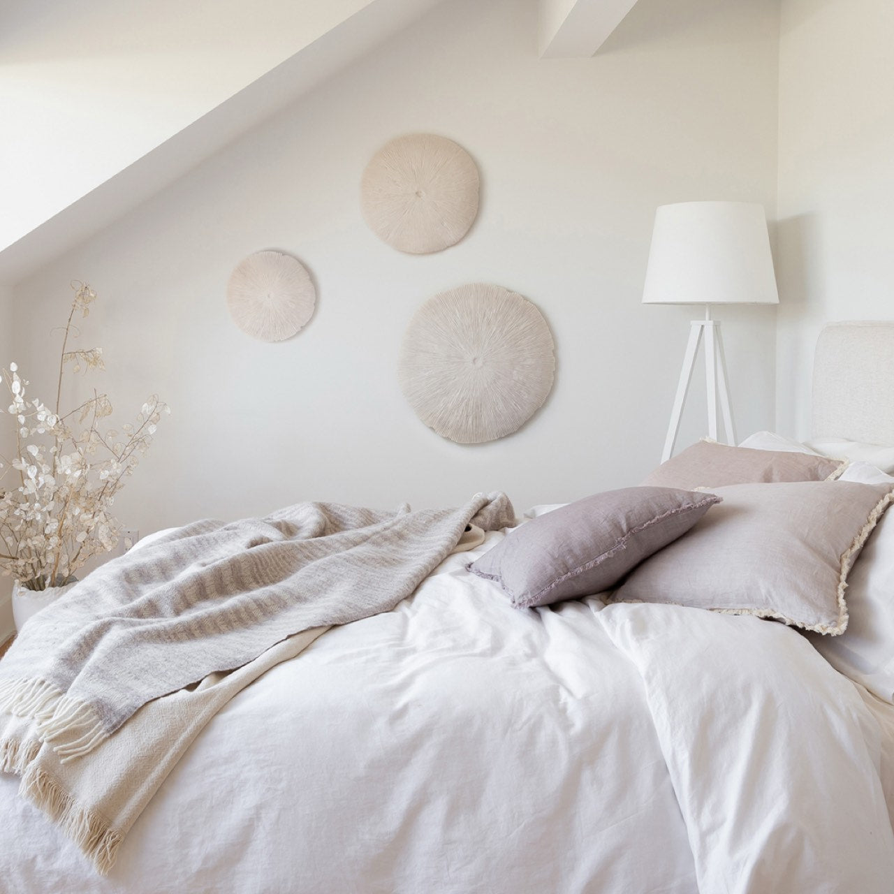 Neatly made bed with white bedding and decorative pillows in a bedroom setting.