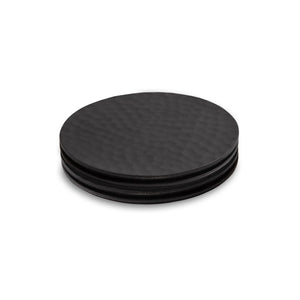 Four black round coasters with a textured surface on a white background