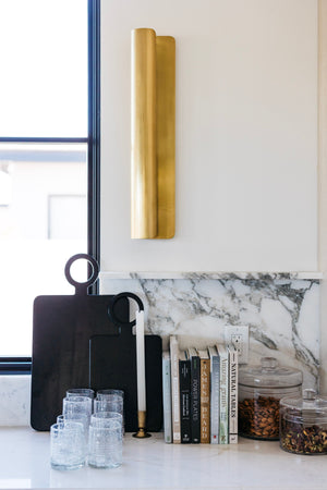 Accord Wall Sconce 5.5" x 25" in aged brass styled in a curated living room for warm, layered light at Laurie Yapp Home.