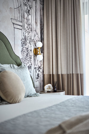 Astoria Wall Sconce in aged brass styled in a warmly lit hallway for warm, layered light at Laurie Yapp Home.