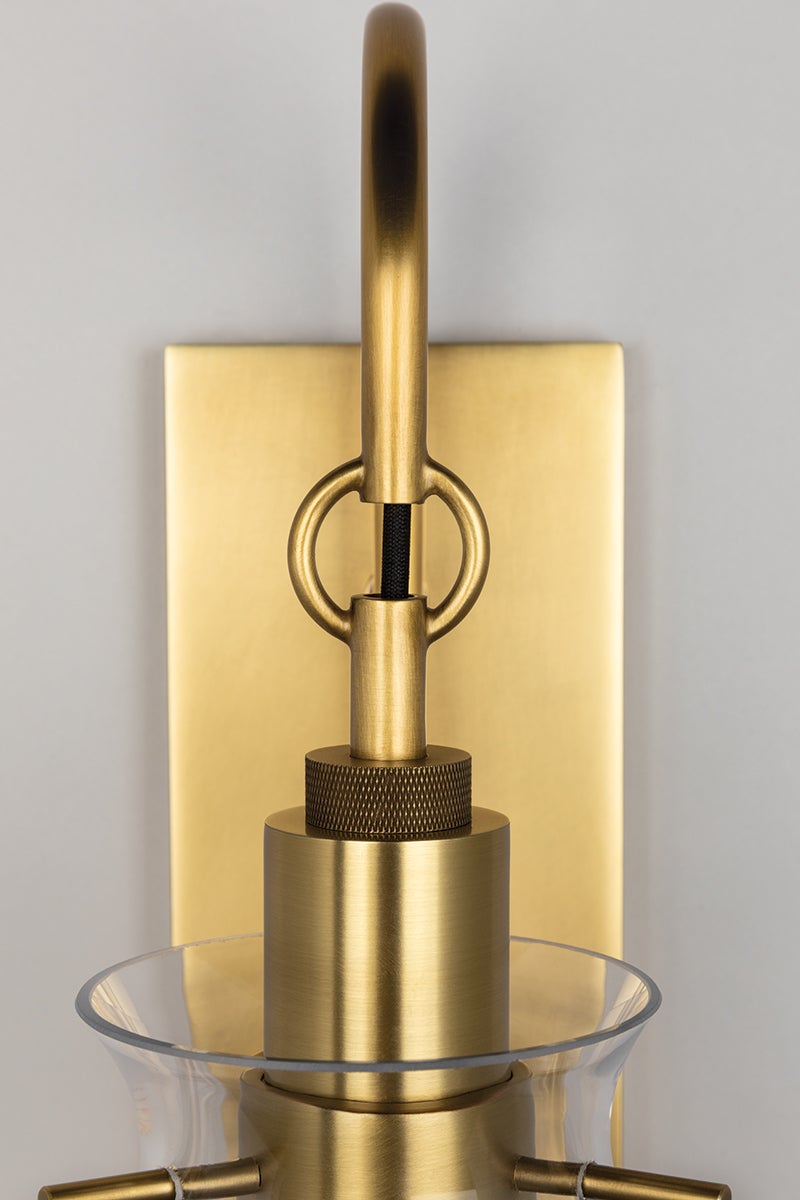 Close-up of the Ivy Wall Sconce in aged brass showing the arm curve and shade silhouette.