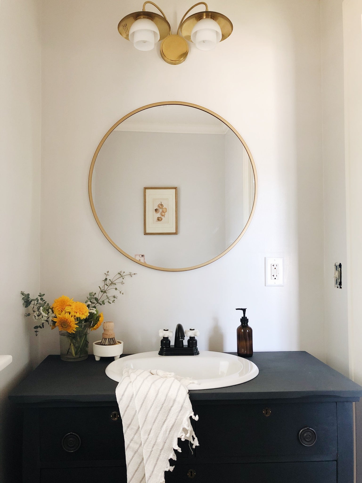 Barron Bath & Vanity in aged brass styled in a bright bathroom for warm, layered light at Laurie Yapp Home.