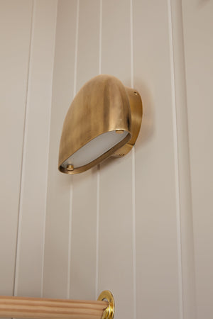 Diggs Wall Sconce in aged brass styled in a modern bathroom for warm, layered light at Laurie Yapp Home.