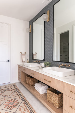 Hinsdale Wall Sconce in aged brass styled in a modern bathroom for warm, layered light at Laurie Yapp Home.