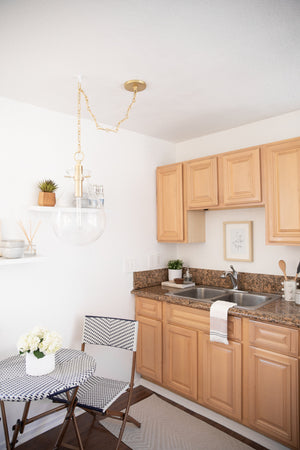 Ivy Pendant 12.5" in aged brass styled in a welcoming entryway for warm, layered light at Laurie Yapp Home.