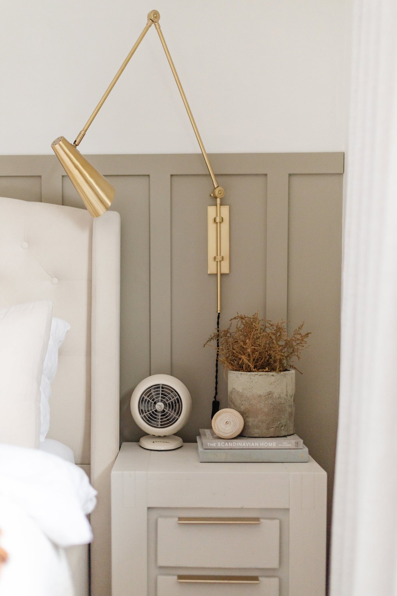 Lorne Plug-In Sconce in aged brass styled in a bedroom for warm, layered light at Laurie Yapp Home.