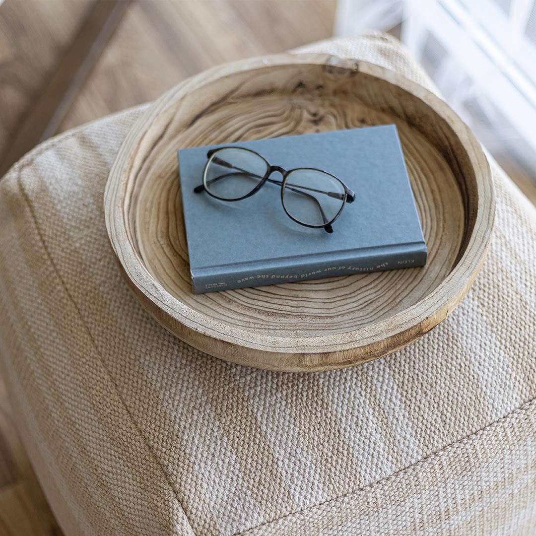 Book with glasses on a wooden tray on a textured surface
