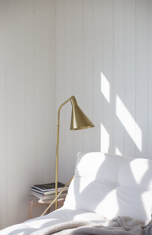 Stanton Floor Lamp in aged brass styled in a living room corner for warm, layered light at Laurie Yapp Home.