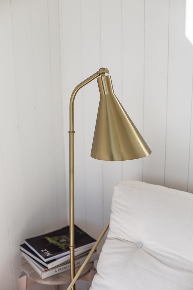 Stanton Floor Lamp in aged brass styled in a reading nook for warm, layered light at Laurie Yapp Home.
