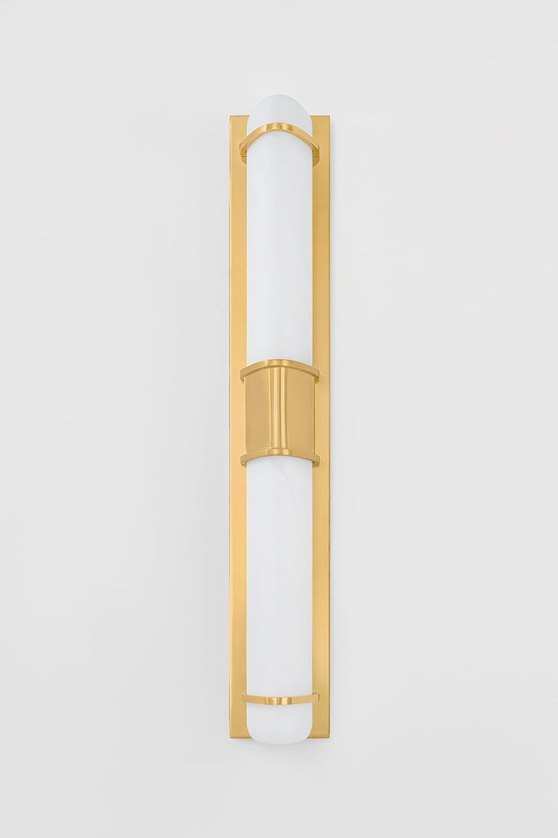 Tottenville Wall Sconce 4.25" x 27" in aged brass shown from the front to reveal the arm curve and shade silhouette.