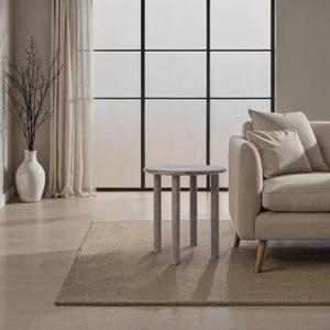 Cetus accent table in a modern living room with a light-colored sofa and large windows.