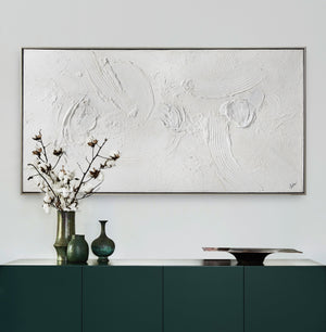 Yanno canvas art featuring textured white abstract design, framed in silver, displayed above a dark green cabinet with vases.