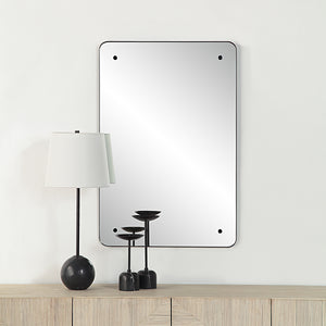 Aine Wall Mirror displayed on a wall above a wooden console with decorative items.