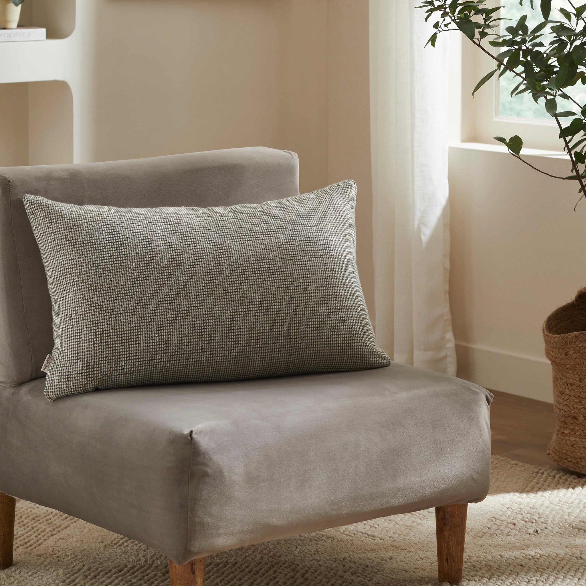 Giverny Indoor Pillow placed on a gray chair, featuring a black and white check pattern.