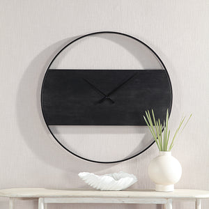 Romy Wall Clock mounted on a wall with decorative vase and bowl below