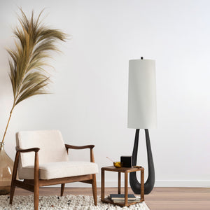 Cornelia floor lamp in a stylish living room setting with a cozy chair and decorative elements.