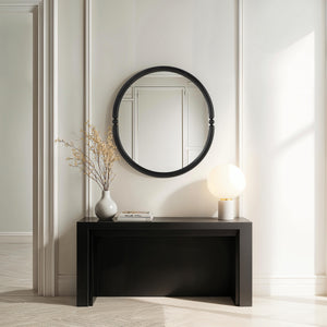 Ditto mirror with a black circular frame, displayed above a sleek black console table with a vase and lamp.