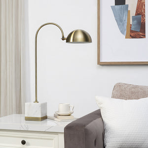 Volos Table Lamp placed on a side table, styled with a cup and books, against a modern decor backdrop.
