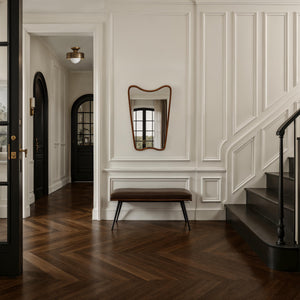 Reverie mirror with a wavy wooden frame, mounted on a white wall in a stylish hallway.