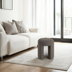 Amarion stool by Renwil placed in a modern living room setting next to a white sofa and large windows