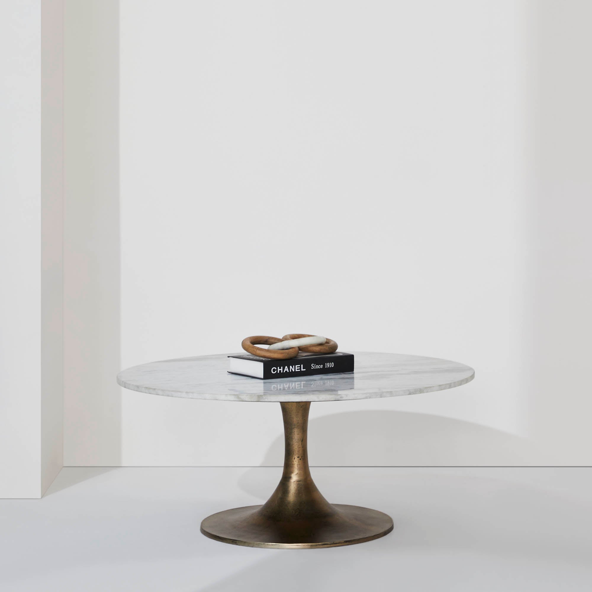 Lovisa Table styled with books and decorative rings on a white background.