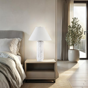 Veda table lamp placed on a nightstand in a cozy bedroom setting with natural light.