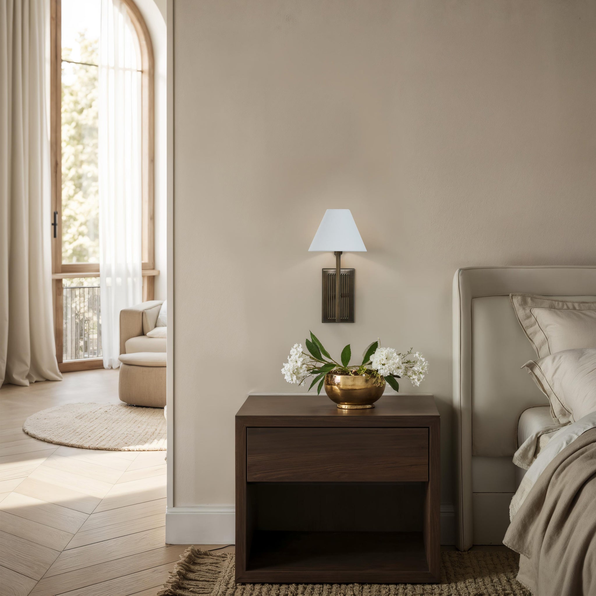 Solaria wall sconce in a bedroom setting, mounted above a nightstand with flowers and a cozy atmosphere.
