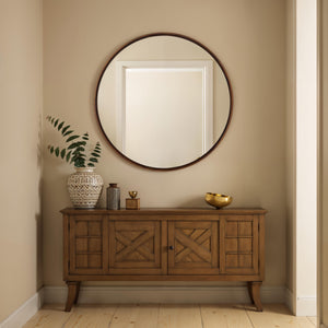 Cabiria mirror with a round frame, displayed above a wooden console table.