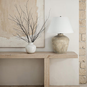 Heritage table lamp on a wooden console table beside a white vase with branches.