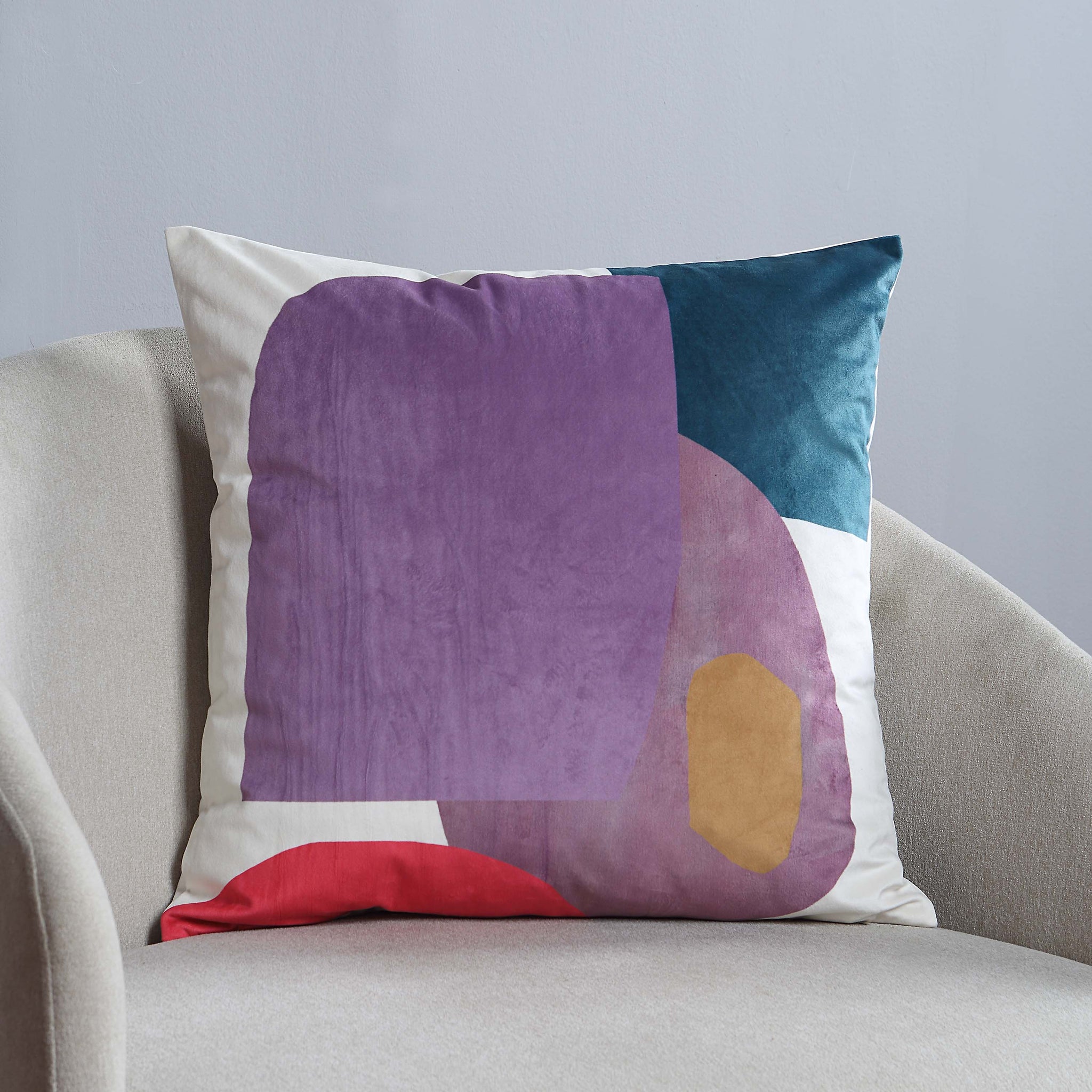 Layla Indoor Pillow displayed on a light gray chair, showcasing abstract design in purple and teal.