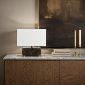 Cabo table lamp on a marble surface next to candles and books.