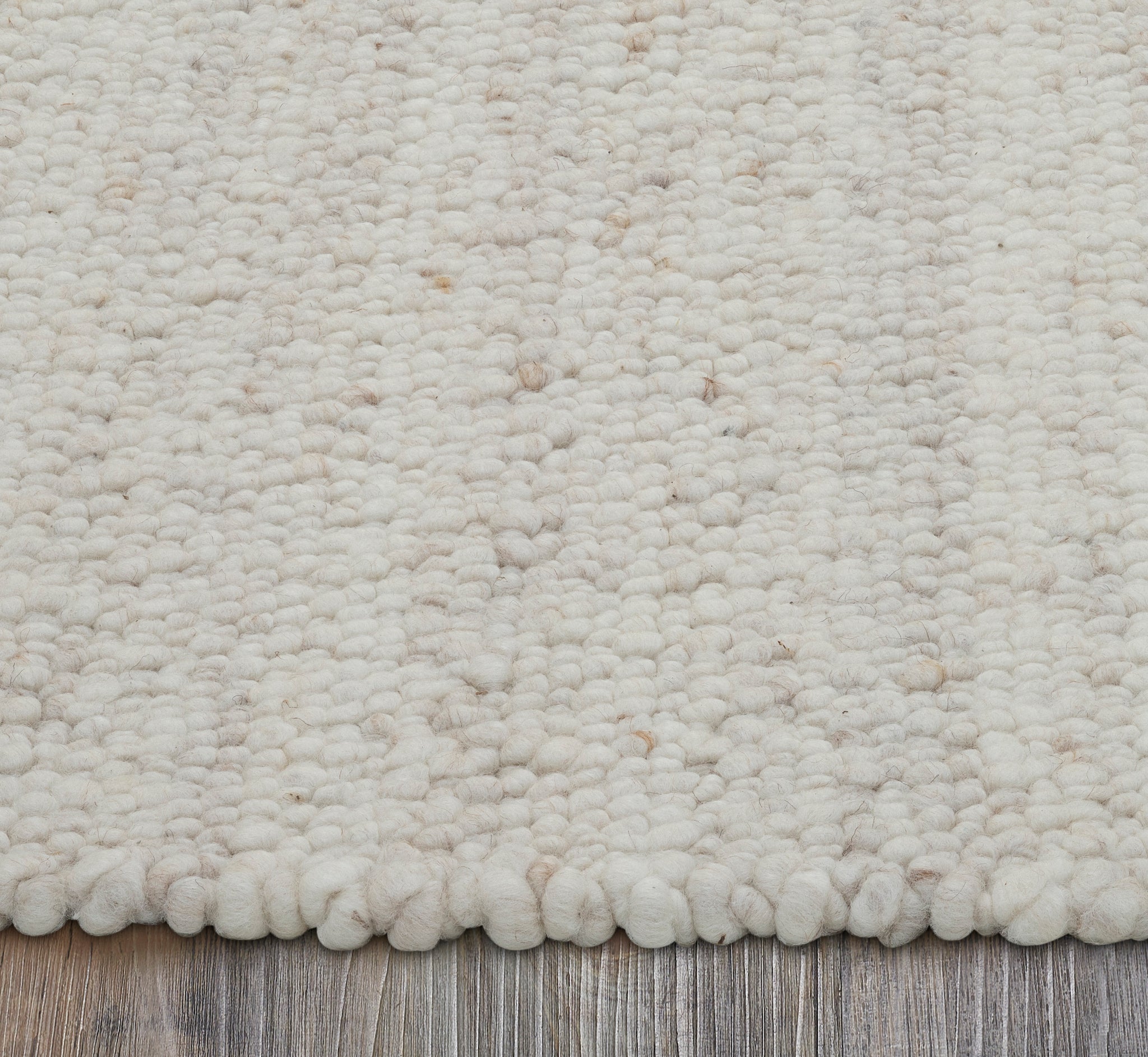 Edge view of Meghan rug highlighting its thick, soft pile in light beige tones.