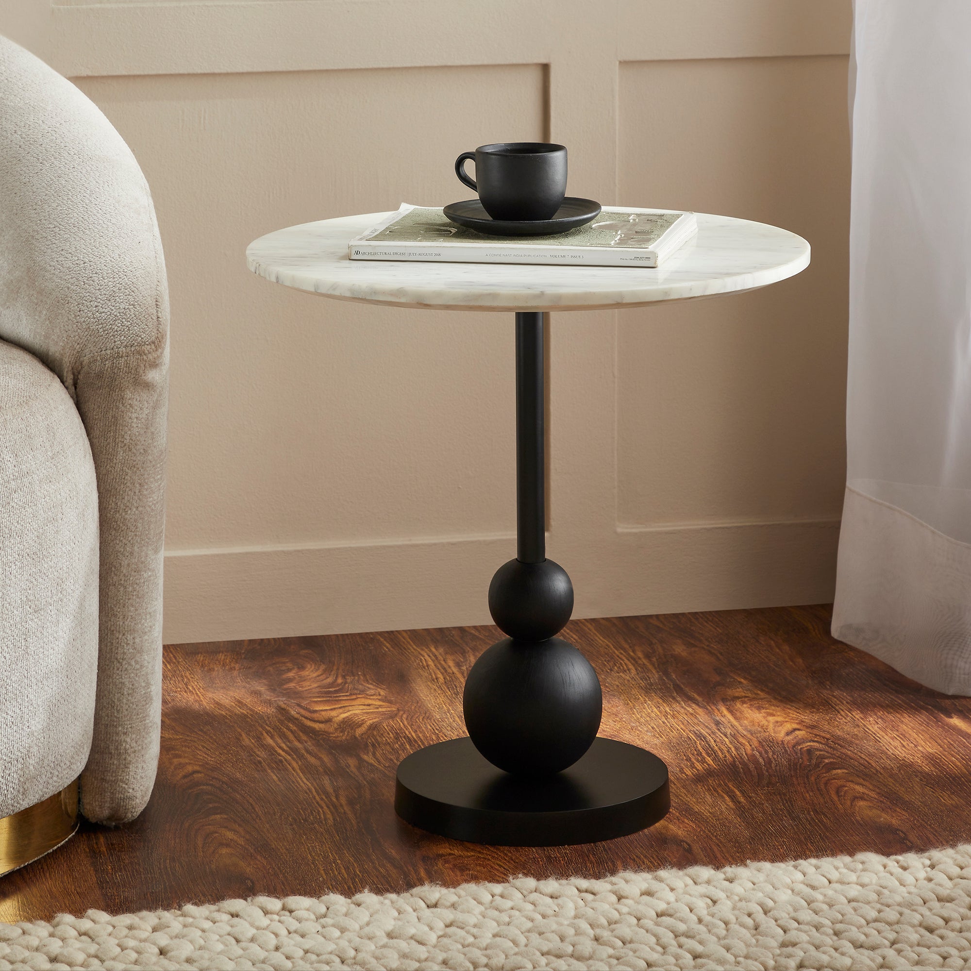 Corrine Table styled with a black cup and plate on its white marble top