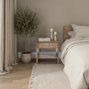 Jaime side table styled in a bedroom with plants and candles, showcasing a cozy decor.