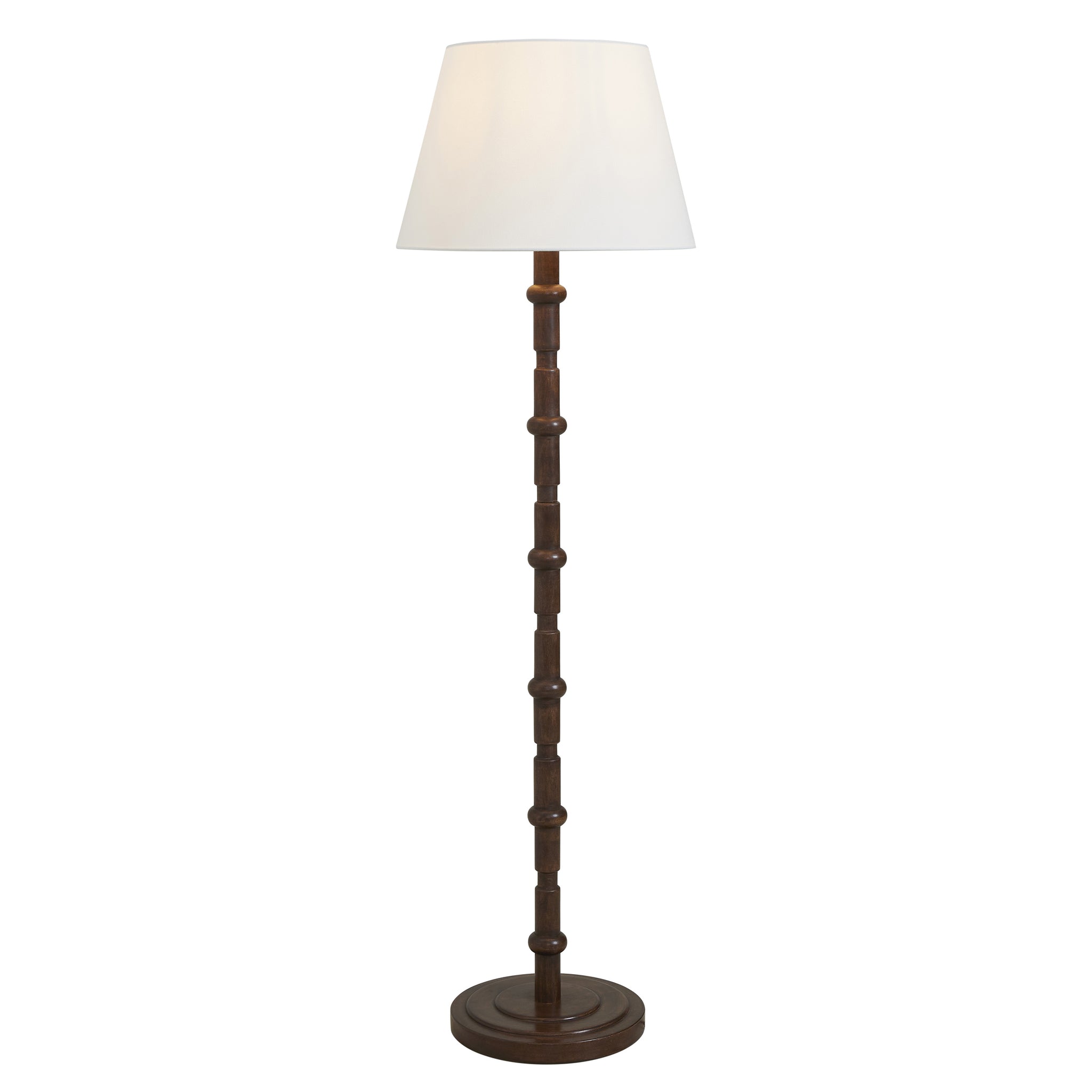 Odlam floor lamp featuring a white shade and dark wood body, illuminated softly.