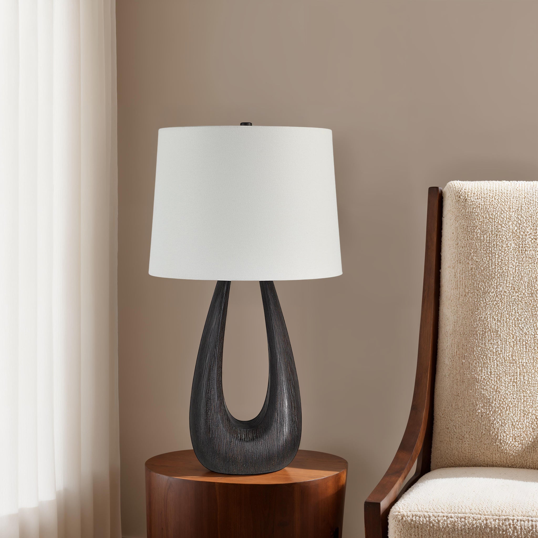 Beckham Table Lamp placed on a wooden side table next to a cozy chair in a softly lit room