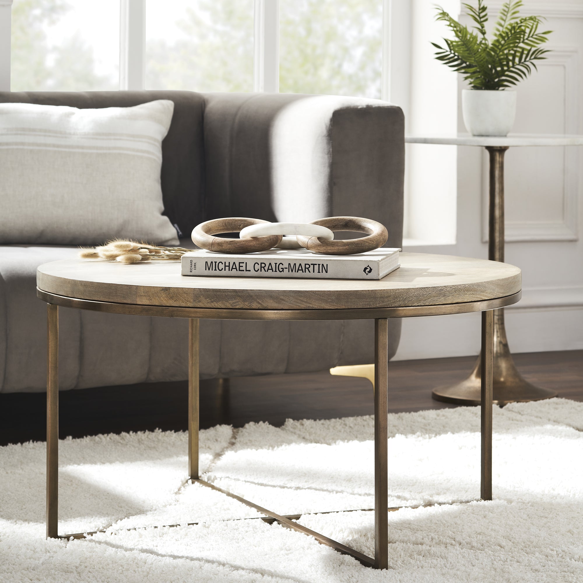 Liana Table styled in a living room setting with a book and decorative rings on top.
