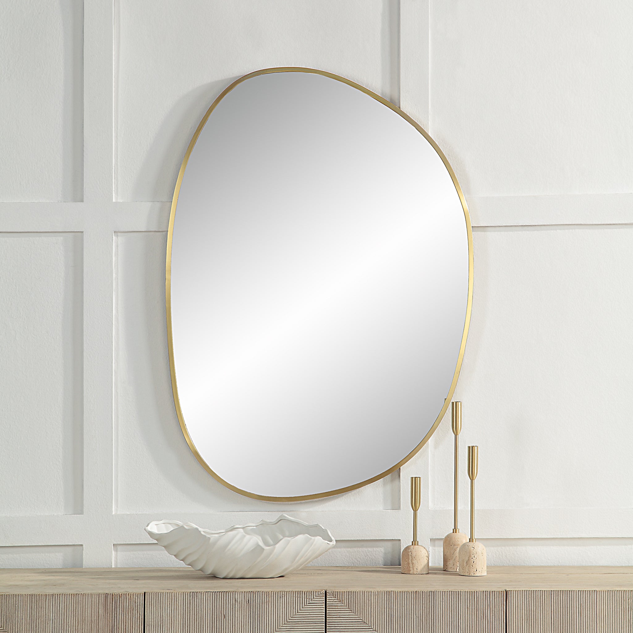 Jyn mirror with a gold frame, mounted on a white wall above a wooden console