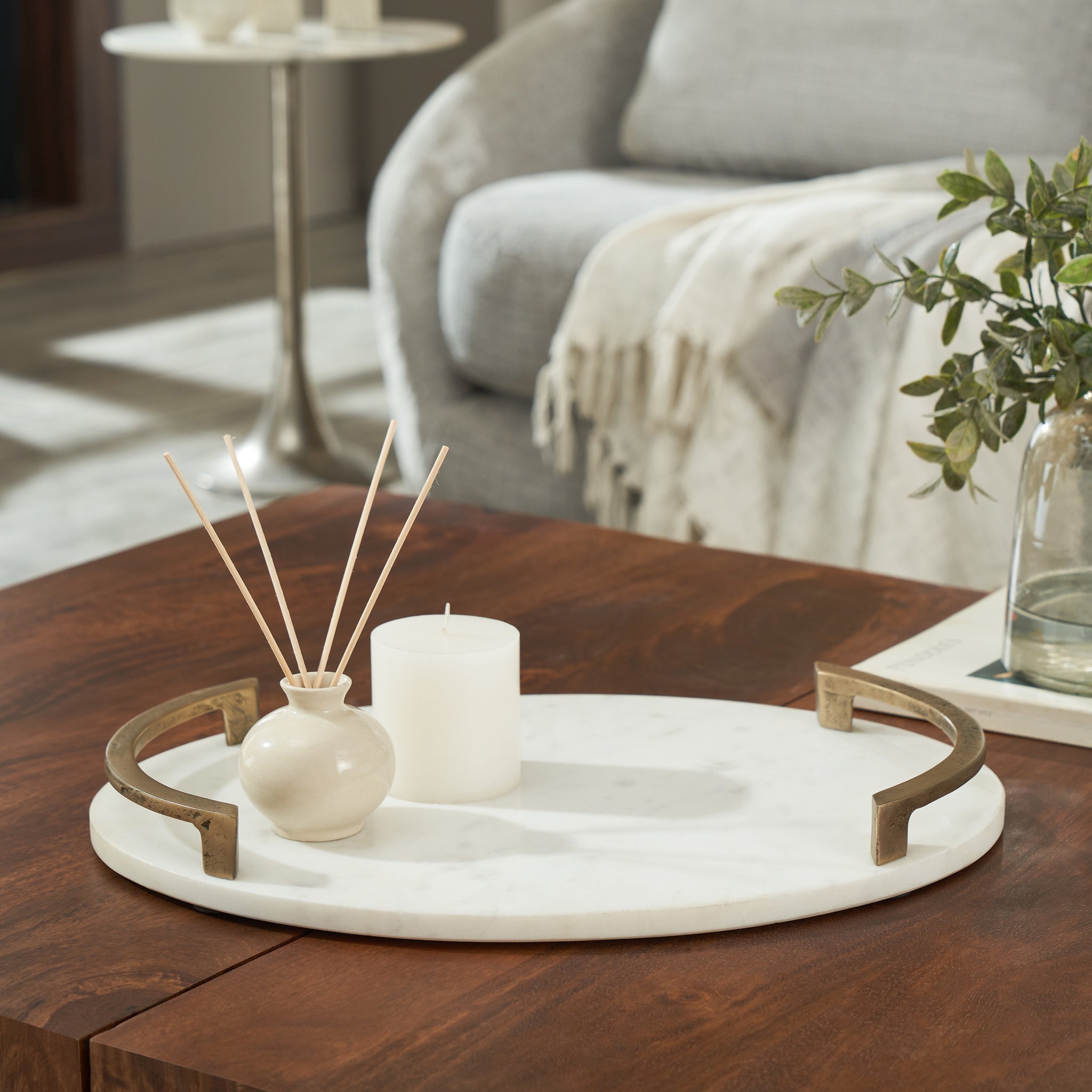 Bianca vase on a wooden table, styled with a candle and decorative sticks.