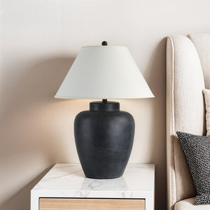 Arancia Table Lamp on a nightstand beside a beige upholstered headboard
