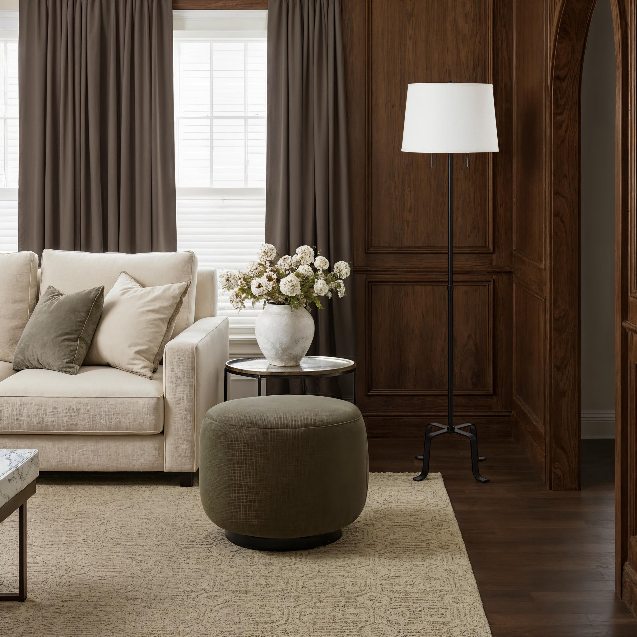 Ruslur floor lamp beside a sofa in a warm-toned living room with decorative elements.