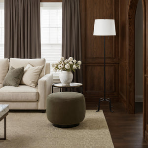 Ruslur floor lamp beside a sofa in a warm-toned living room with decorative elements.