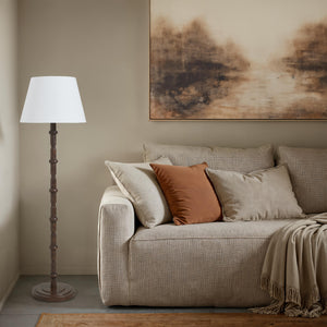 Odlam floor lamp next to a light-colored sofa adorned with pillows and a throw.