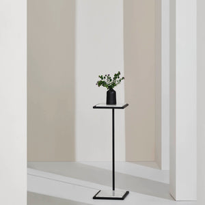 Danica Table by Renwil styled with a black vase and greenery, set against a minimalist background.