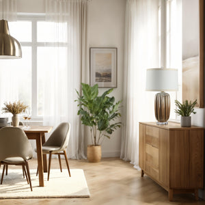 Lumeo table lamp on a wooden sideboard in a bright dining room with plants.