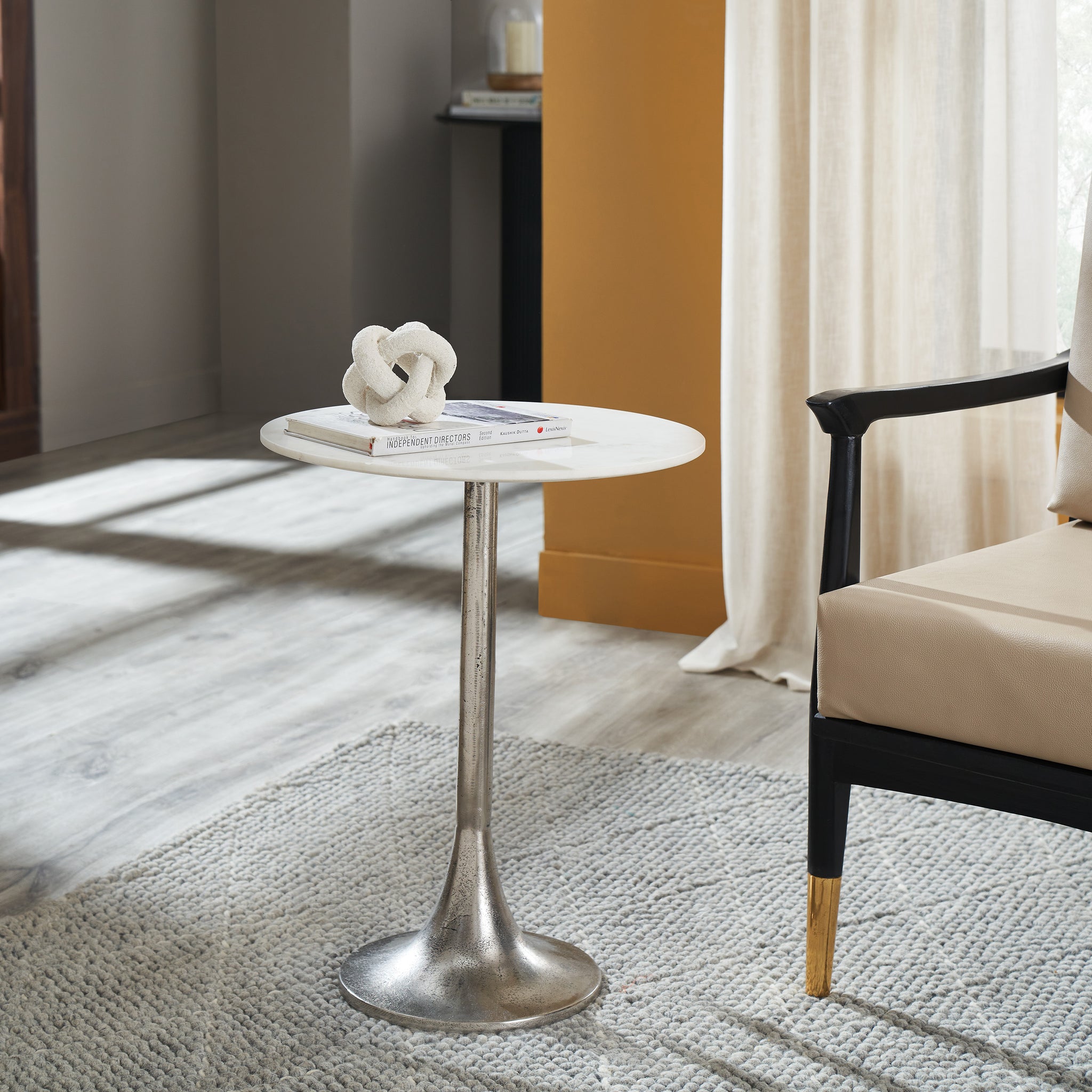 Eloa table with a white marble top, books, and a decorative knot on top