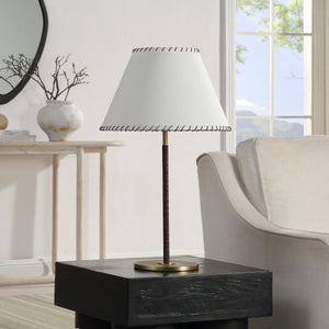Camelia Table Lamp placed on a black side table in a bright room with a white sofa.